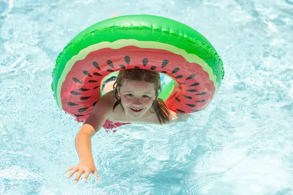 Child relaxing in pool. Kid swimming with float ring in water pool. Funny kids summer face