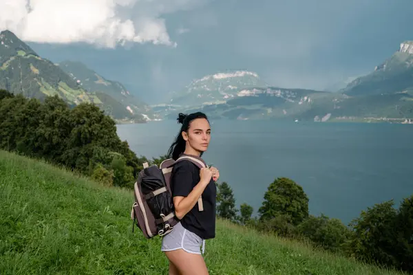 Freedom traveler woman with backpack enjoying a beautiful nature. Travel woman alps mountains. Alps summer. Woman with backpack hiking. Lifestyle adventure concept forest and lake into the wild