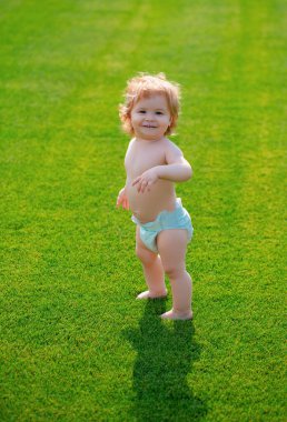 Şirin, komik, gülen bebek emeklemeyi öğreniyor çimlerde oynayıp, bahçede yazı izlerken eğleniyor. Aile hayatında mutluluk ve uyum.