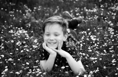 Çimlerin üzerinde bahar çocuğu. Tarla çiçeğindeki sevimli çocuk. Rüya gören çocuk