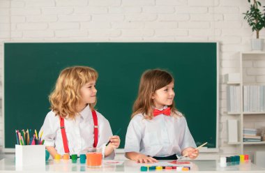 Çocukların yaratıcı eğitimi. Okullu çocuklar sınıfta kurşun kalemle renkli resimler çiziyorlar. Sanat ve zanaat dersinden zevk alan sevimli öğrencilerin portresi.