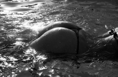 Sexy buttocks in pool closeup, summer journey, sensual woman with hot natural butt relax in water. Wet body, ass in sexy bikini. Seduction and pleasure model. Luxury passion buttocks