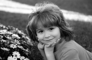 Çiçek açan yaz bahçesinde çiçek toplayan sevimli küçük çocuk. Bahar çocuğu suratı. Yazın çimlerin üzerinde çiçeklerle mutlu küçük bir çocuk. Bahçedeki çayırda küçük şirin bir çocuk.