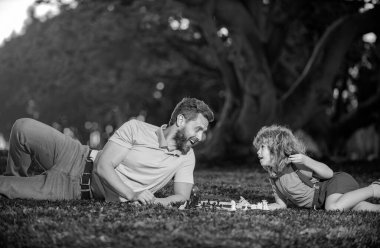 Baba oğul çim parkında çimlerde satranç oynuyorlar. Babalar Günü, aileyi sevmek, ebeveynlik, çocukluk konsepti. Akıllı çocuk, akıllı çocuklar.