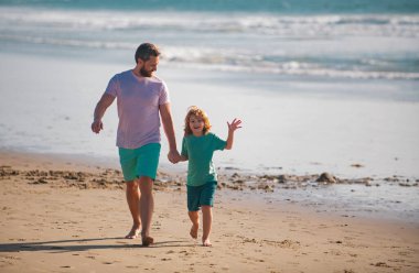 Baba ve oğul denizde yürüyor. Baba ve çocuk dışarıda oynuyor, bahar gününün tadını çıkarın.
