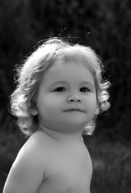 Kafanı yaklaştır. Baby 'nin yakın plan fotoğrafını çek. Çocuk yüzü, yeşil doğa parkında küçük çocuk portresi.