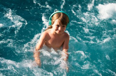 Küçük mutlu çocuk yazın yüzme havuzunda eğleniyor. Aile tatili