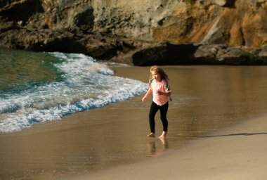 Kumsalda koşan çocuk. Mutlu çocuk yaz tatilinde denizde koşar. Koşmak ve çocuklar için sağlıklı spor