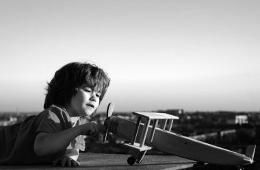 Kids playing with vintage wooden airplane outdoors. Portrait of children against summer sky background. Travel and freedom concept. Summer holidays with children