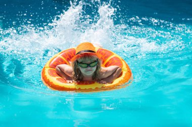 Yüzme havuzundaki çocuk şişme halkada. Çocuk turuncu şamandırayla yüzüyor. Su oyuncağı, çocuklar için sağlıklı açık hava sporları. Çocuklar plaj eğlencesi