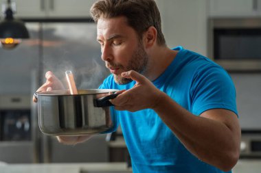 Adam mutfakta yemek pişiriyor. Şef aşçı tencereli bir yemek hazırlıyor. Menü tarifi sağlıklı yemek. Evde yemek pişiren adam mutfakta yemek hazırlıyor. Olgun bir adam mutfakta yemek hazırlıyor.