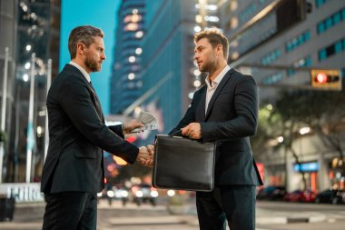 İş adamlarının büyüme stratejisi. İş adamları tekliflerini müşteriye sundular. İş adamları para veriyor. Gece şehrinde kolaj için para teklif eden bir iş adamı. İş için para teklif ediyor.