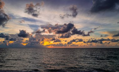 Gün batımı deniz manzarası. Günbatımı, yaz tatili geçmişi. Sakin dalgalarla renkli sahil gündoğumu. Doğa deniz göğü. Mavi gökyüzüne ve denize karşı farklı renkte bulutlarla gün doğumu