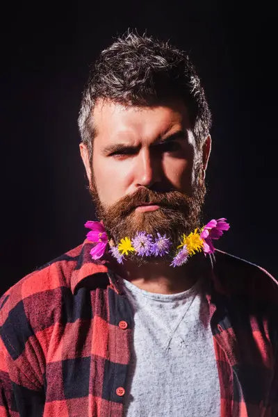 A bearded man with a decorated beard for the Spring holiday. Flower in the beard. Barber shop. Man hair beauty. Beard Care and Facial Hair. Beard Styles for barbers