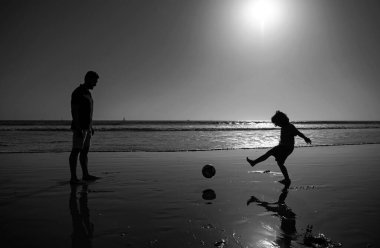 Baba ve oğul sahilde futbol ya da futbol oynarlar. Baba ve çocuk bir yaz günü oynuyorlar.