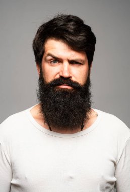 Kendine güvenen ciddi bir adamın portresi sakalı ve bıyığı var, ciddi ve izole görünüyor. Stüdyodaki hippi adam modelleri. İş adamı düşüncesi. Sakallı, şık saçlı, yakışıklı bir erkek.