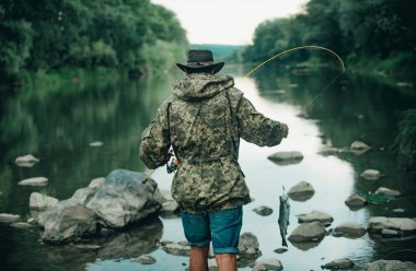 Nehirdeki balıkçı ya da oltayla göldeki balıkçı. Balıkçılık hobisi ve bahar haftasonu. Sakallı adam olta ve ağıyla balıkçı
