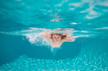 Child swimming underwater in swimming pool. Funny kids boy play and swim in the sea water. Summer kids in water in pool underwater