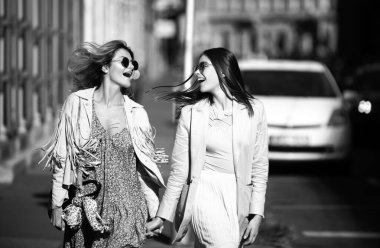 Şehirde yürüyen güneş gözlüklü iki genç kadın. Eğlenceli tatil, romantik seyahat.