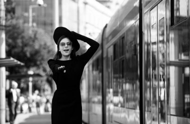 Şehir caddesinde tramvay otobüsünün peşinden koşan güzel genç bir kadın. Güzel, genç bir moda kadını. Şehirde seyahat etmek.