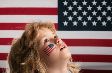 Çocuk 4 Temmuz 'da bağımsızlığını kutluyor. Amerika Birleşik Devletleri kavramı. Amerikan bayrağı taşıyan çocuk. Anma günü. Yanağında Amerikan bayrağı olan komik çocuklar. Amerikalı vatansever, hayran