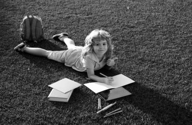 Dışarıda kitap okuyan sevimli bir çocuk. Çocuk parkta kitap okudu. Okul ve uluslararası okuryazarlık günü için hazırlık. Okul konseptine dönelim.