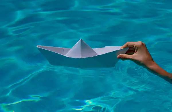 Hand holding paper boat on the sea background. Paper boat in hands on sea water background. Tourism and traveling, travel dreams vacation holiday, sailing adventure