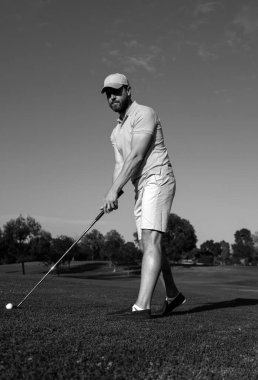 Golfçü adam güzel, güneşli yeşil golf sahasında golf oynuyor.
