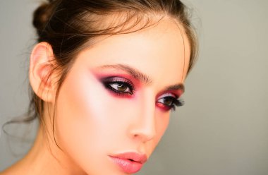 Stüdyoda gri arka planda güzel bir kadın var. Yakın plan portre. Moda, güzellik, kozmetik. Makyaj, pürüzsüz cilt