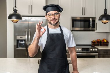 Chef cook with ok sign, delicious food. Portrait of chef man in a chef cap in the kitchen. Man wearing apron and chefs uniform and chefs hat. Character kitchener, chef for advertising