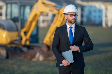 İnşaat alanında mimar. İnşaat alanında kask ve takım elbiseli mimar. İnşaatta duran kendine güvenen bir mimar. Yatırımcı ya da inşaat mühendisi. İspanyol 'un açık hava portresi