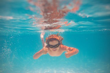 Çocuk yüzme havuzunda suya dalıyor. Küçük çocuk havuzda su altında yüzüyor. Çocuk su altında ya da havuzda yüzüyor. Yaz tatili eğlencesi. Yüzme havuzundaki su altı portresi