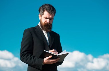 Gökyüzü olan bir iş adamı. Fotokopi defteri tutan ciddi bir adamın fotokopi uzayı ve gökyüzü arka planında düşünceli bir ifadeyle kalem.