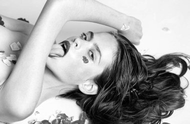 Kendini sev. Yala, Tutku. Baştan çıkarıcı ve seksi. Şehvetli doğa kızı. Parfüm, kozmetik konsepti. Güllerin üzerinde güzel genç bir kadın. Bahar ve yazın ilhamı