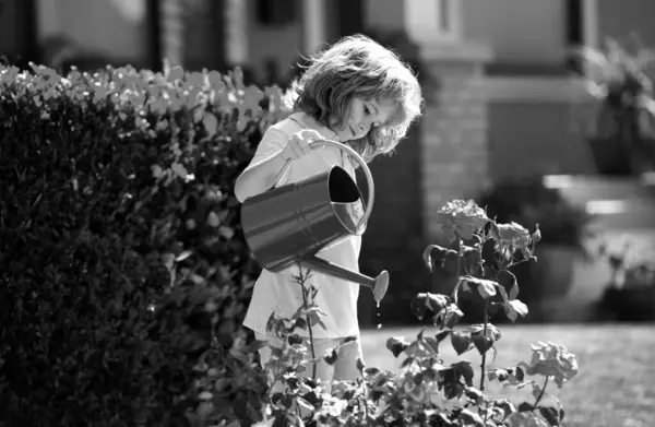 庭の植え付けの花で散水缶を持つ子供農家 — ストック写真