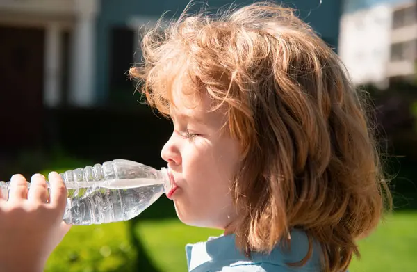 Portrait of a cute child boy drinking water from bottle. Close up caucasian kids face. Closeup head of funny kid