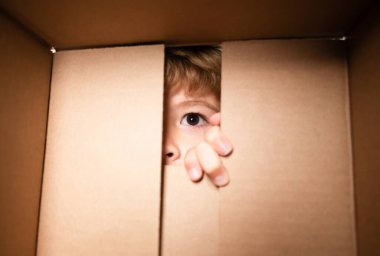 Çocuk 6 yaşında, açık bir karton kutuda, paket açık ve kapalı karton kutular. Paketleme veya açma kavramı