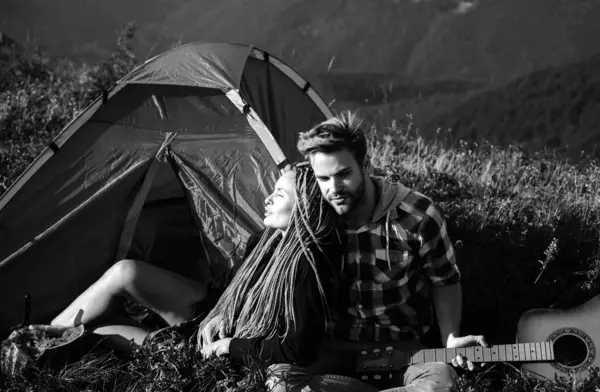 Romantic couple in love camping outdoors and sitting near tent. Happy Man and woman on a romantic camping vacation