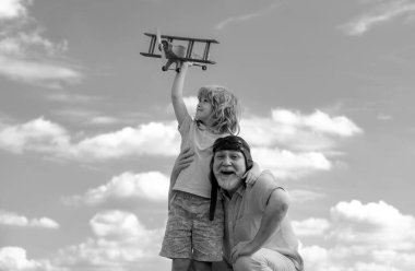 Torunum ve büyükbabam, oyuncak jetleriyle gökyüzüne doğru uçuyorlar. Seyahat hayali kuran çocuk pilot pilot.