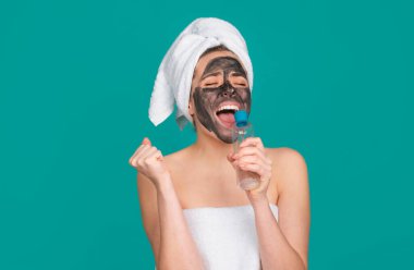 Kozmetik çamur yüz prosedürü olan heyecanlı, güzel bir kadın, spa sağlık konsepti. Cilt bakımı güzellik tedavisi. Havlu kafaya. Tıbbi mineral çamuru