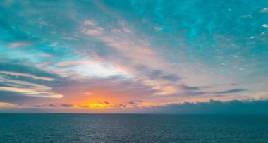 Gökyüzünde gün batımı ve renkli bulutlar. Güneş doğarken sakin bir deniz, Hawaii.