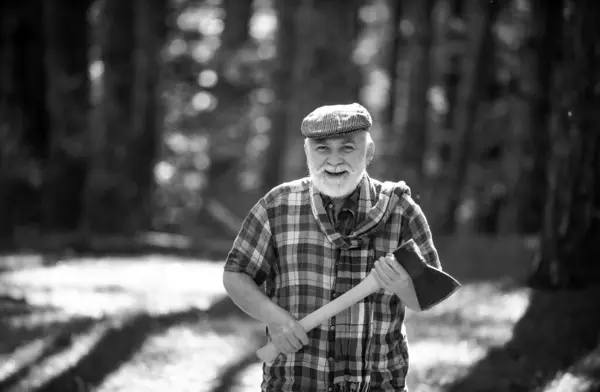 Hiking in deep wood. Sunny weather. Portrait of smiling man. Fashion portrait man. Natural background. Old bearded man with axe. Human and nature. Funny bearded forester