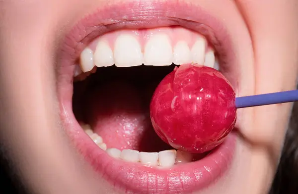 Sexy red lips with candy for print. Red sweet lollipop in the mouth in art design. Glossy womans lips licking sucking lollipop. Sensual sexy mouth with candy concept enjoyment beautiful female lips