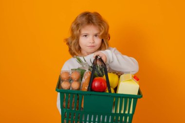 İndirim ve indirim. Elinde alışveriş sepeti olan çocuk. Çocuk alışverişte. Alışveriş arabası olan küçük bir çocuk. Süpermarket ve bakkal. Alışveriş, indirim, satış konsepti