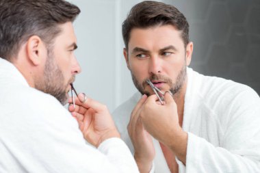 Kafkasyalı bir adam tek başına makasla saç kesmeye çalışıyor. Erkek tıraşı. Berber makası, berber dükkanı. Berber makası. Saç kesme konsepti. Erkek saç stili ve saç kesimi