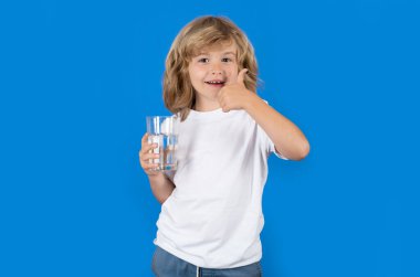 Stüdyoda izole edilmiş çocuk içme suyu. Çocuk saf maden suyunun tadını çıkarıyor. Susamış çocuk su bardağı tutuyor. Sağlıklı sudan ferahlatıcıya