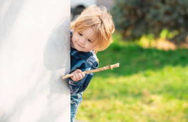 Outdoor cute little boy playing hide and seek. Adorable child having fun in the park. Childhood