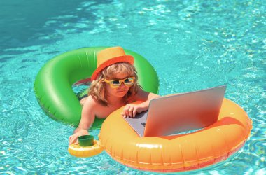 Çocuk yüzme havuzunda dizüstü bilgisayarla çalışıyor.