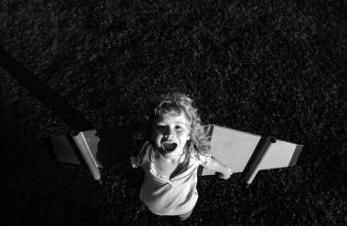 Sırt çantası kanatlı gülen çocuk gezgin. Pilot pilotçuluk oynayan ve parkta hayaller kuran bir çocuk.