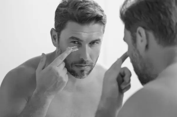 stock image Sexy sensual man with perfect skin touch face after shaving. Skin care healthcare cosmetic procedures concept. Close up man looking in mirror, sensitive skin, cosmetology treatment. Skin care